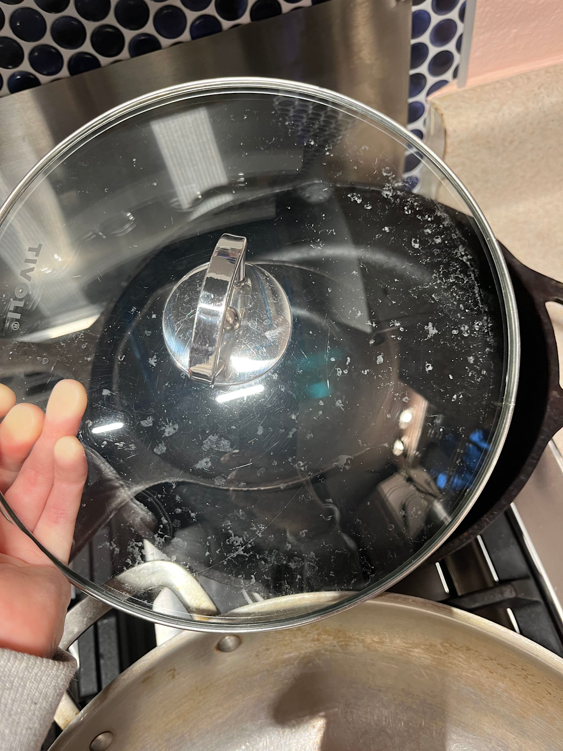A glass lid with white residue spots from undissolved detergent or mineral deposits, illustrating dishwasher tablet dissolution issues