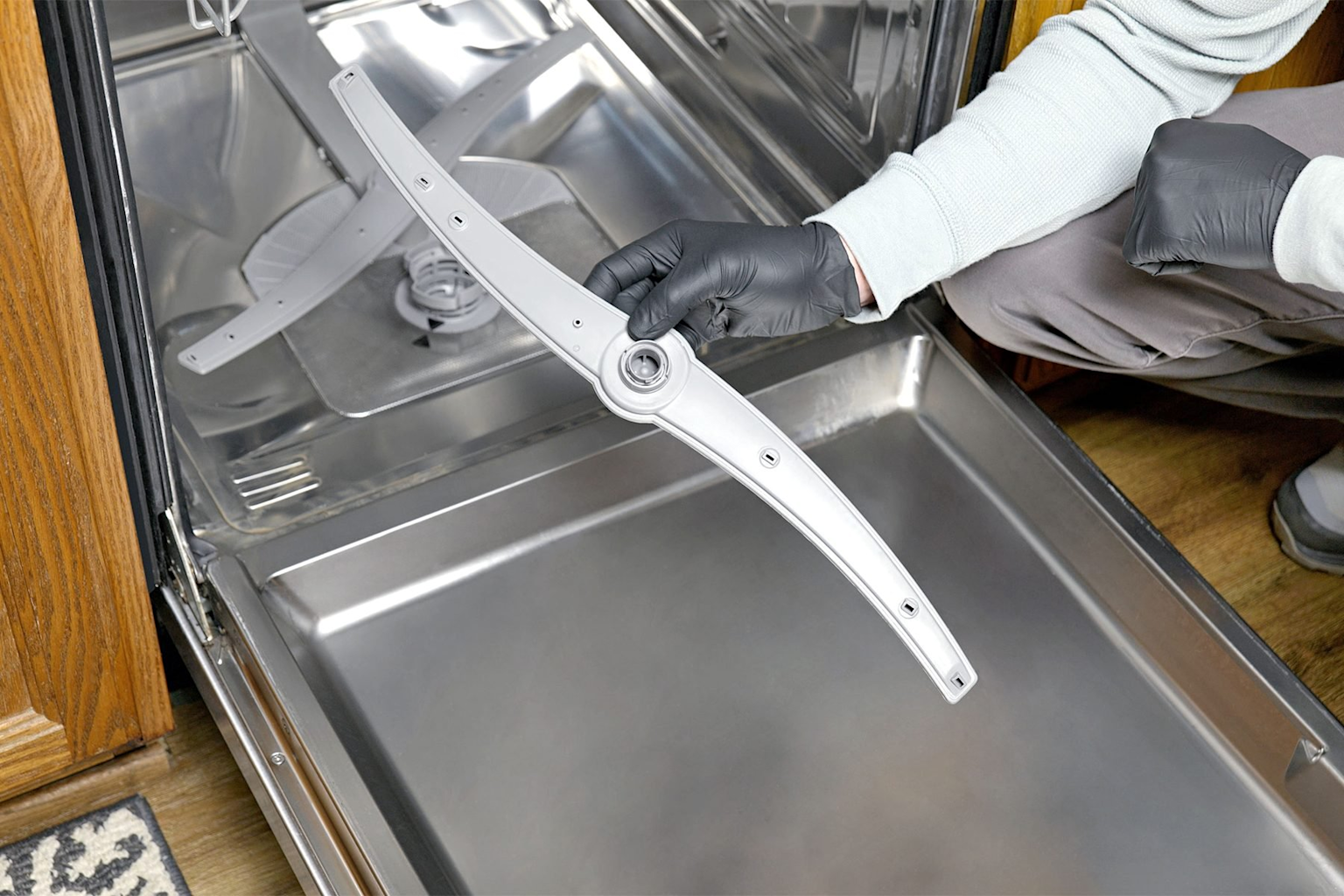 Removing and inspecting a dishwasher spray arm to ensure it isn't blocked and water flows freely, which helps tablets dissolve properly
